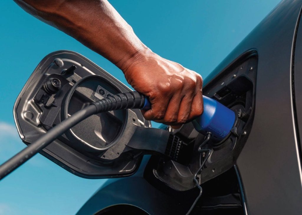 Driver plugging a charging connector into the Toyota bZ4X charge port