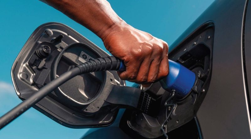 Driver plugging a charging connector into the Toyota bZ4X charge port